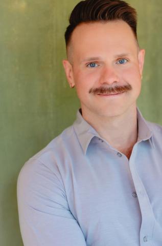 Jamey Grisham, a white man in a blue button up. He has a mustache. 